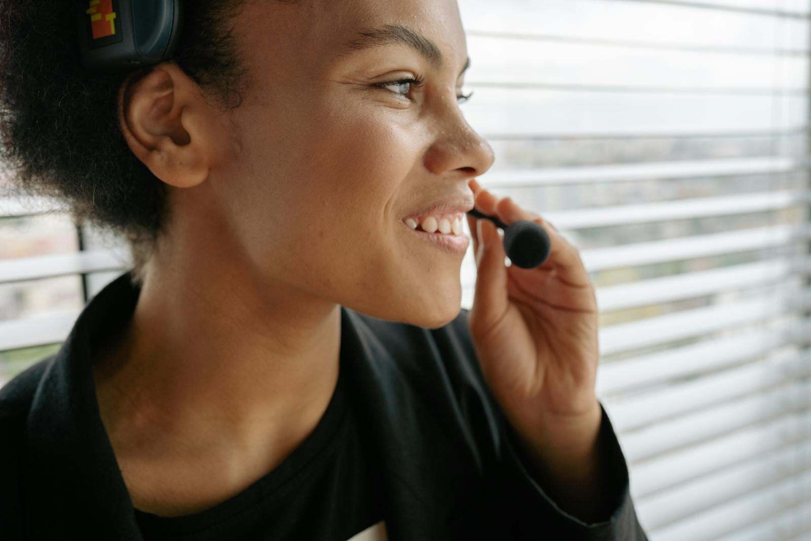 Gros plan d'une femme souriante utilisant un casque, idéal pour les thèmes liés au service à la clientèle.